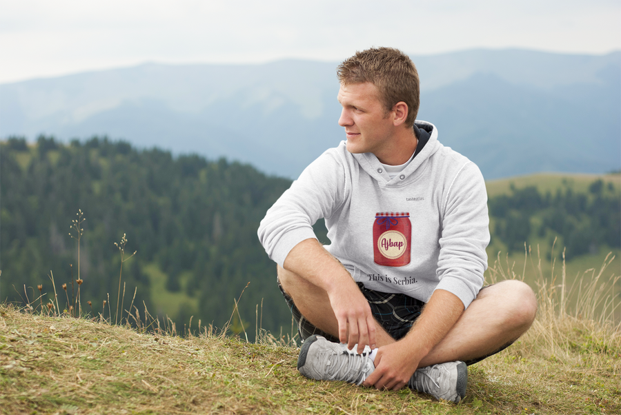 a man sitting on a hill wearing ajvar hoodie