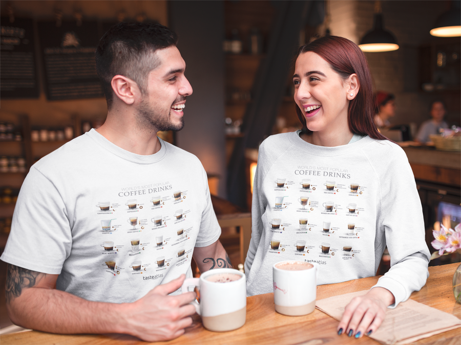 woman sitting drinking coffee and wearing world's most popular coffee drinks sweatshirt