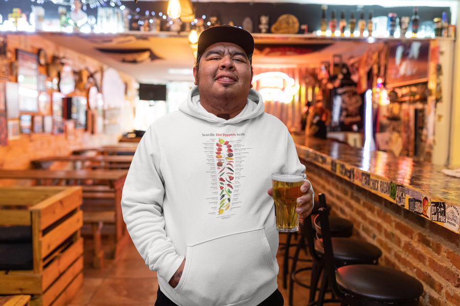 a man in a bar holding a glass of beer wearing scoville hot peppers scale hoodie